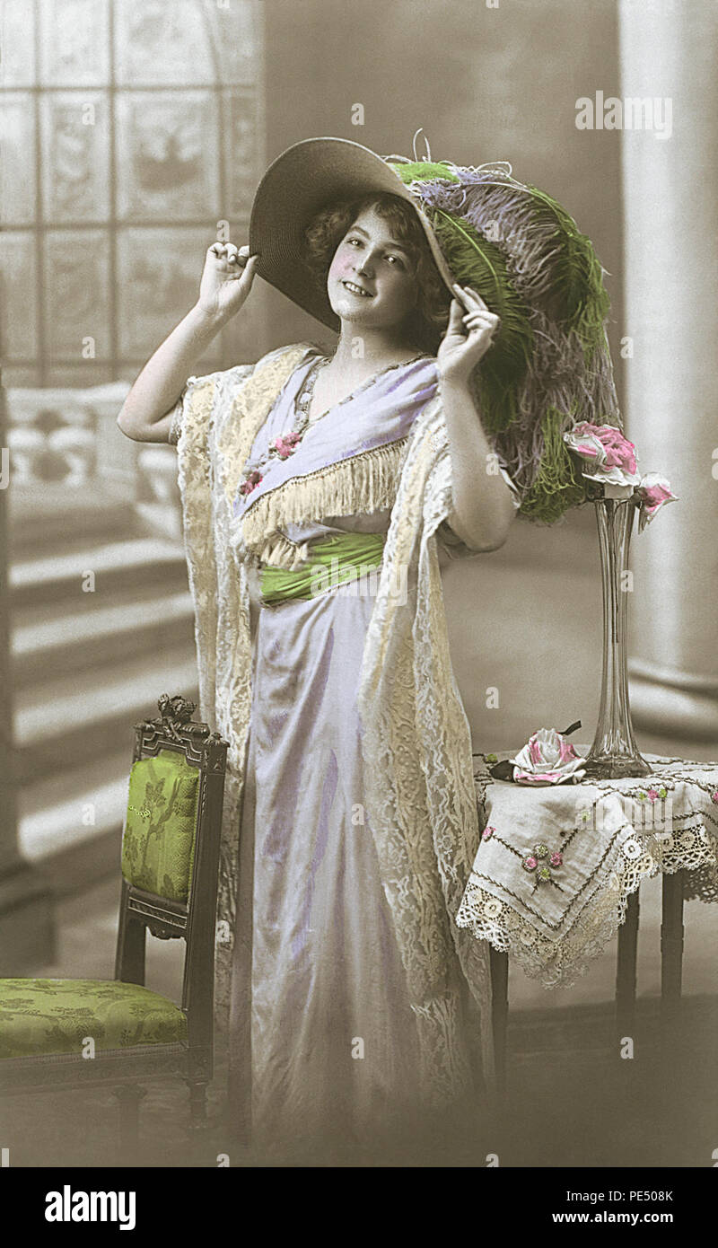 Vintage, hand-tinted, sepia, Edwardian postcard showing a beautiful woman in a picture hat. Stock Photo