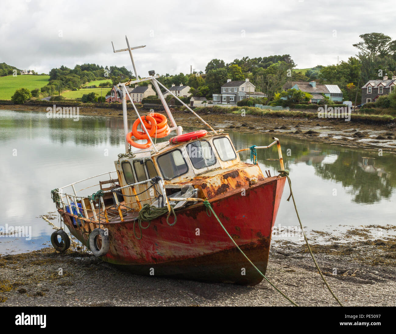rusty, rusting ship wrecked hull tied up on a creek shore line. Stock Photo