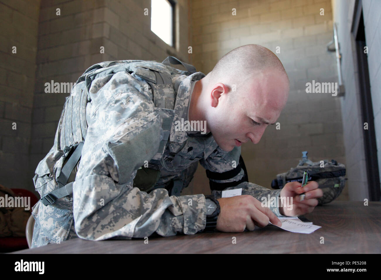 U.S. Army Spc. Adam Walton, assigned to AMC Band, U.S. Army Materiel Command, writes a SALUTE report during an exercise for the U.S. Army's Best Warrior Competition in Fort A.P. Hill, Va., Oct. 6, 2015. The competition is a grueling, weeklong event that tests the skills, knowledge, and professionalism of 26 warriors representing 13 commands. (U.S. Army photo by Pfc. Michael Parnell/Released) #BestWarrior Stock Photo