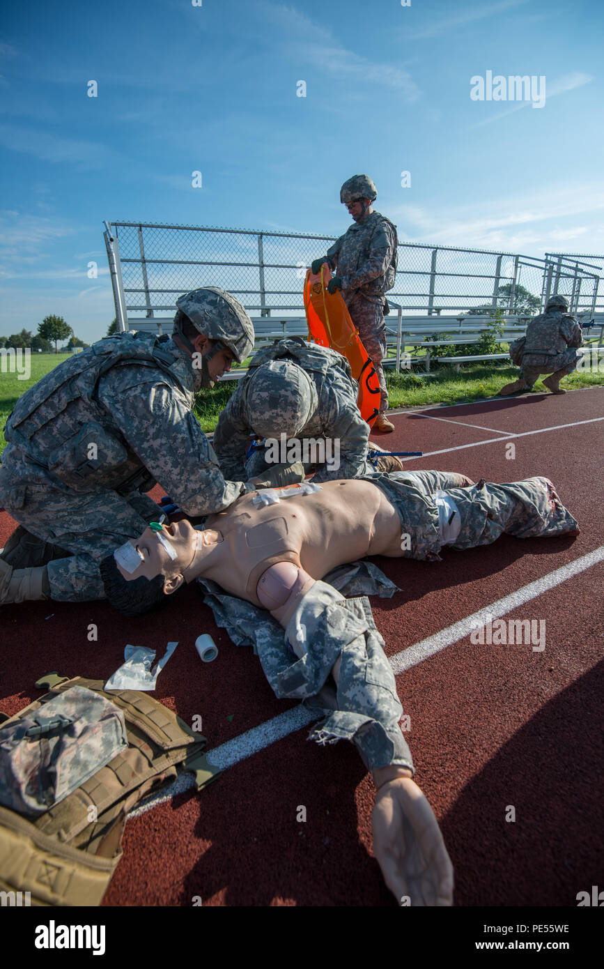 U.S. Army Sgt. Carlos Flores, with 128th Signal Company, and Pfc. Zachary Rehm, assigned to Headquarters and Headquarters Detachment (HHD), 39th Signal Battalion, treat wounds on a training mannequin, while Cpt. Phillip Gilchirst, commander of HHD, 39th Signal Battalion, prepares a flexible stretcher, as they perform Combat Life Saver exercises for the Battalion's Commander's Prime Time Training, on Chièvres Air Base, Chièvres, Belgium, Sept. 21, 2015. (U.S. Army photo by Visual Information Specialist Pierre-Etienne Courtejoie/Released) Stock Photo