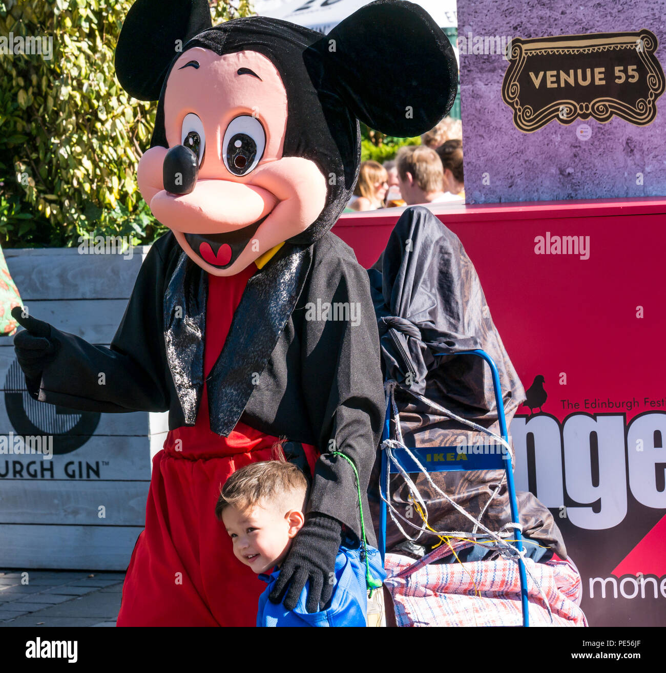 Young boy posing for photo with busker in Mickey Mouse costume, The Mound, Princes Street, Edinburgh, Scotland, UK during festival season Stock Photo