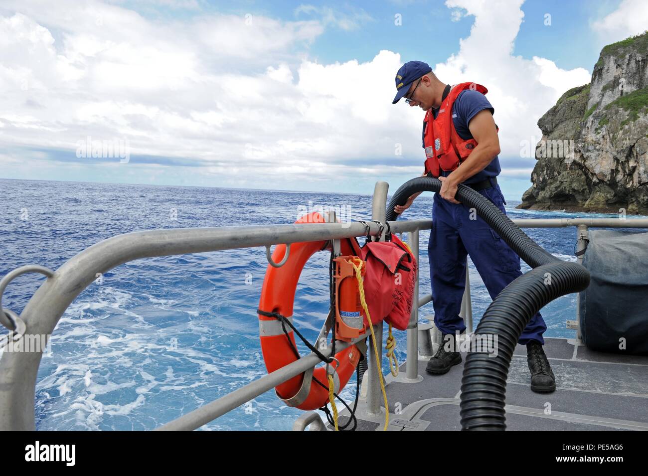 150930-N-ZB122-006 SANTA RITA, GUAM (Sept. 30, 2015) – Off the coast of Naval Base Guam, U.S. Coast Guard  Boatswain's Mate 3rd Class John Jordan-Bertucci demonstrates how to use the hose of a Honda de-watering portable pump (p-6) used for removing excess water on boats, Sept. 30. Based on Naval Base Guam, the U.S. Coast Guard Apra Harbor's primary missions here include search and rescue, law enforcement and protecting of living marine resources and critical infrastructures in and under the water. (U.S. Navy photo by Mass Communication Specialist 2nd Class Chelsy Alamina/Released) Stock Photo