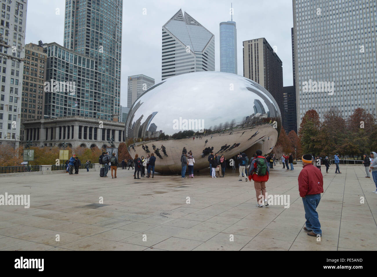 The Urban Icon Bean Sculpture At Millennium Park In Chicago Illinois With Tourists and Buildings In the Background On a Grey Winter's Day Stock Photo