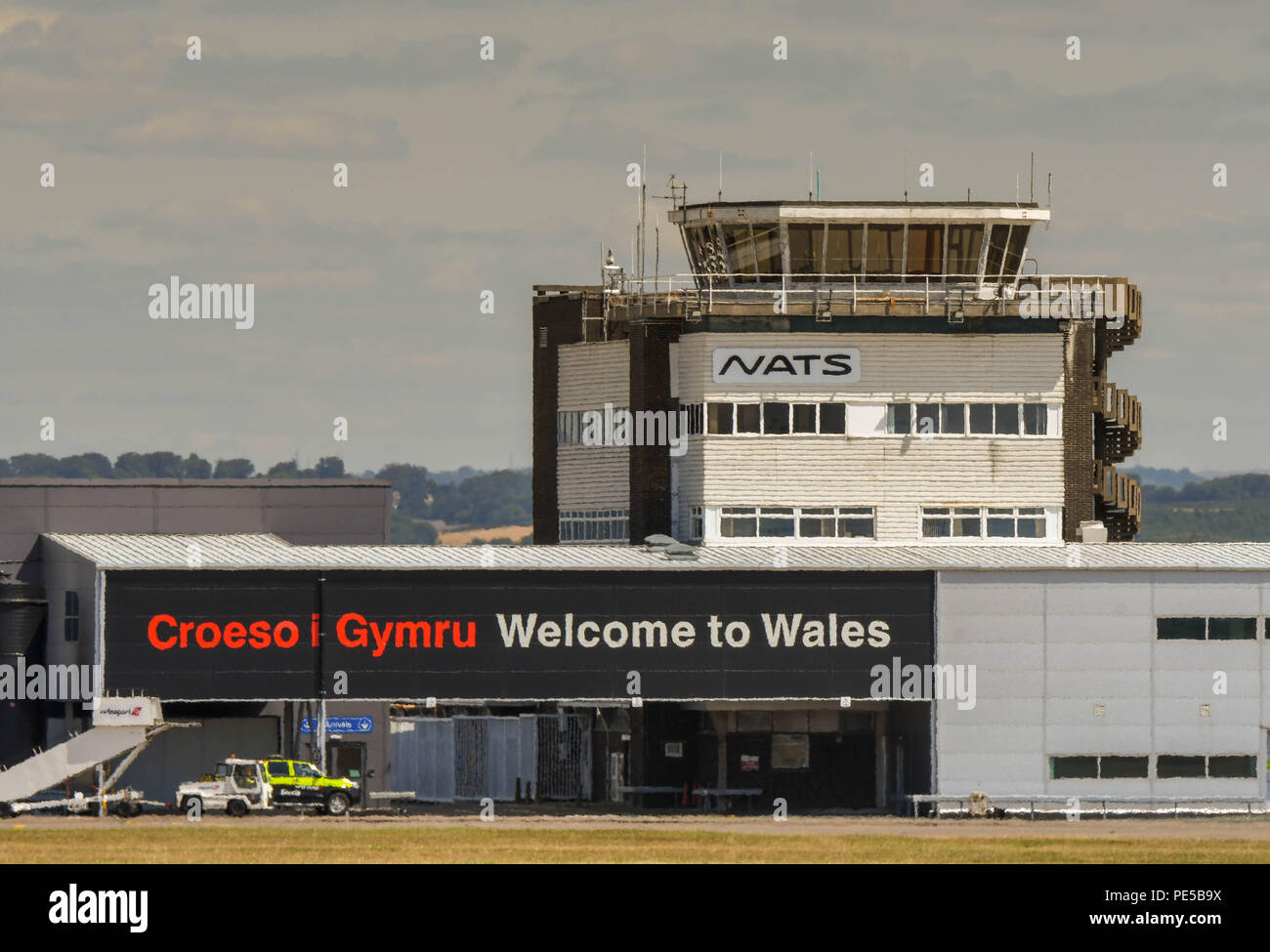 Terminal building and control tower at Cardiff Wales Airport. There is a bilingual Welcome to Wales sign on the side of the building. Stock Photo