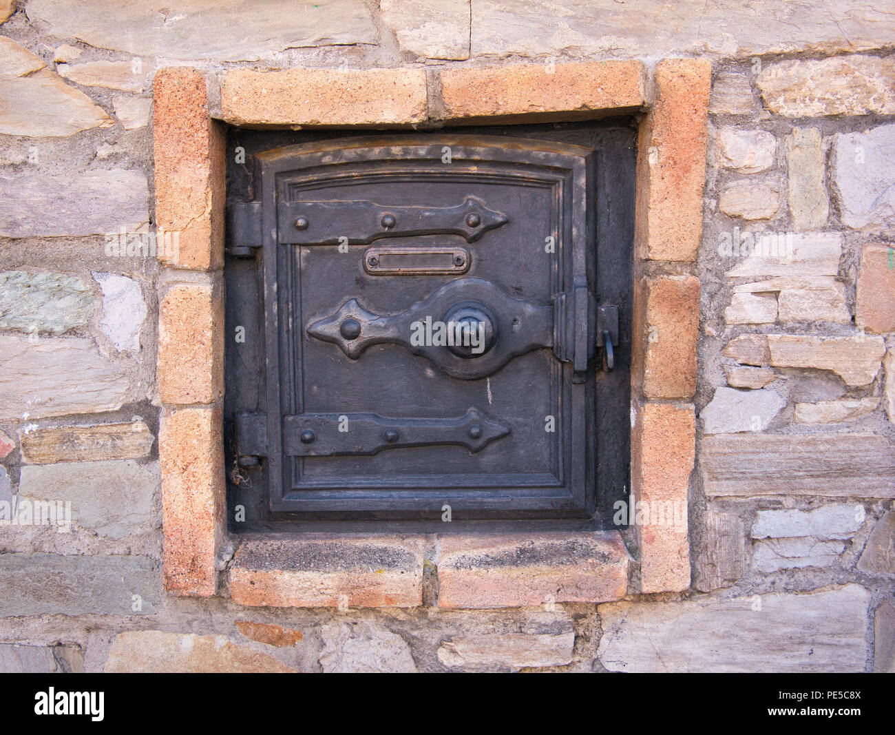 Iron door from an old oven outside on the facade with stones Stock Photo
