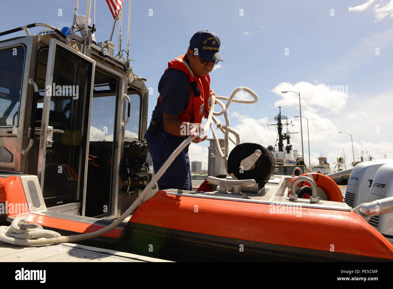 Petty Officer 1st Class Carlos Lopez, a machinery technician at Station Honolulu, handles mooring lines aboard a 29-foot Response Boat-Small (29249) at the station’s pier, Sept. 28, 2015. The RB-S II, designed with an increased emphasis on function and crew comfort, will replace the Defender-class RB-S as the older assets reach the end of their service life. (U.S. Coast Guard photo by Petty Officer 3rd Class Melissa E. McKenzie/Released) Stock Photo