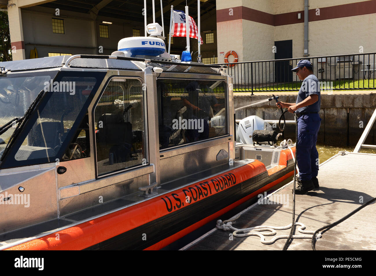 Petty Officer 1st Class Carlos Lopez, a machinery technician at Coast Guard Station Honolulu, sprays down a 29-foot Response Boat-Small (29249) at the station’s pier after a Honolulu Harbor patrol, Sept. 28, 2015. The RB-S II, designed with an increased emphasis on function and crew comfort, will replace the Defender-class RB-S as the older assets reach the end of their service life. (U.S. Coast Guard photo by Petty Officer 3rd Class Melissa E. McKenzie/Released) Stock Photo