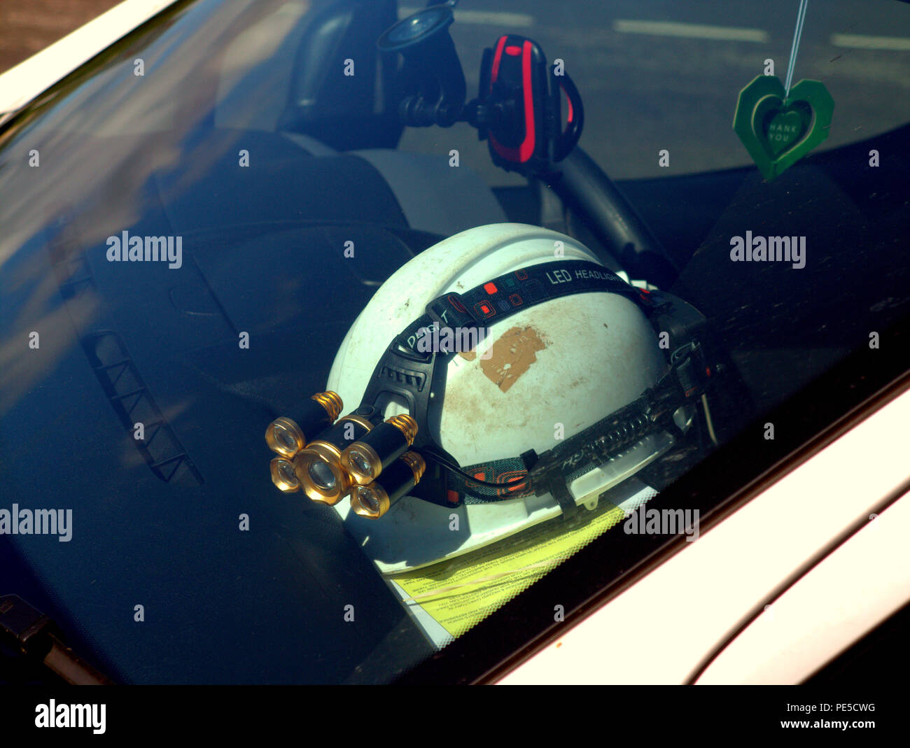 construction industry helmet in the windscreen of a car with light led modern pit helmet type with documents or forms Stock Photo