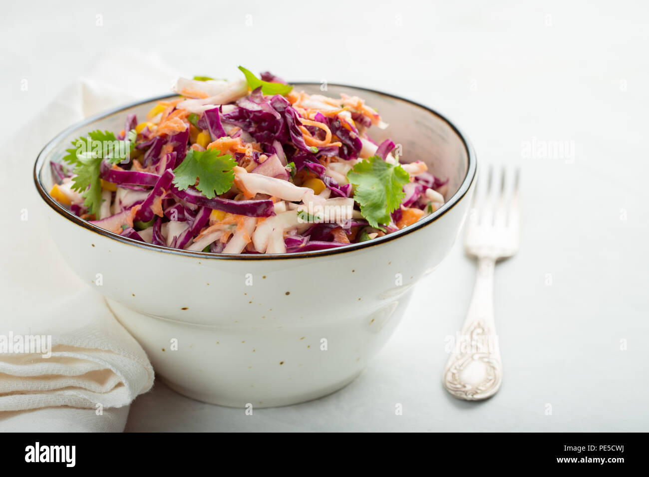 Purple cabbage and carrot salad with mayonnaise in a white bowl on a light background. Classic coleslaw. Diet vegetarian dish. Copy space Stock Photo