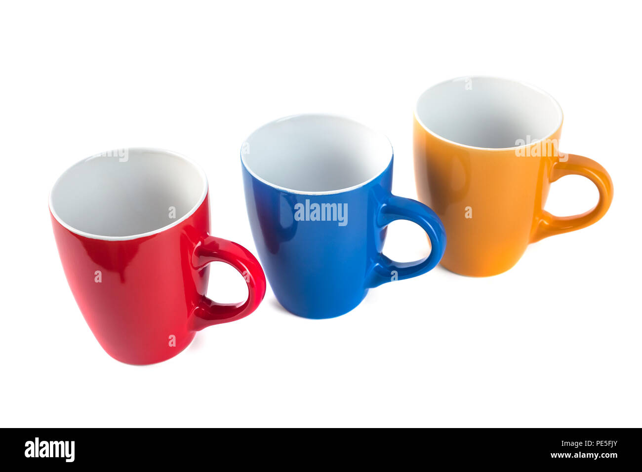 Three color ceramic cups on a white background. Stock Photo