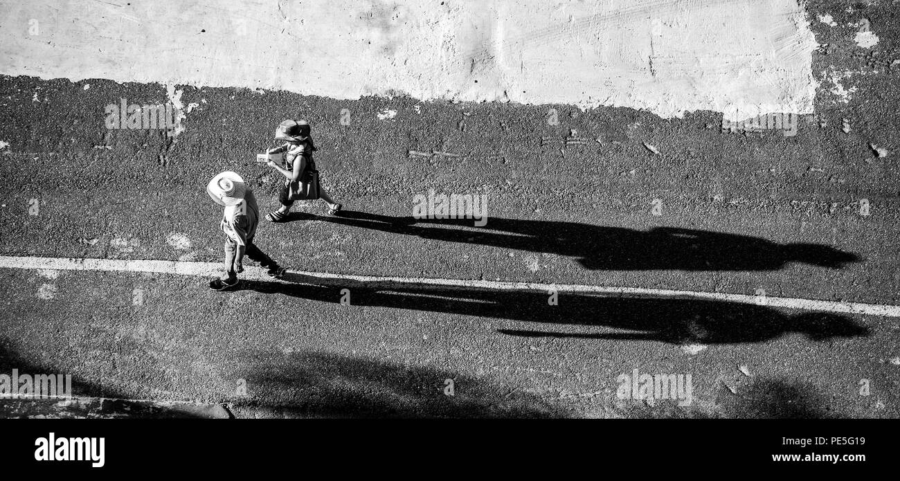 Silhouette of a man and a woman in hats casting long shadows on an ...
