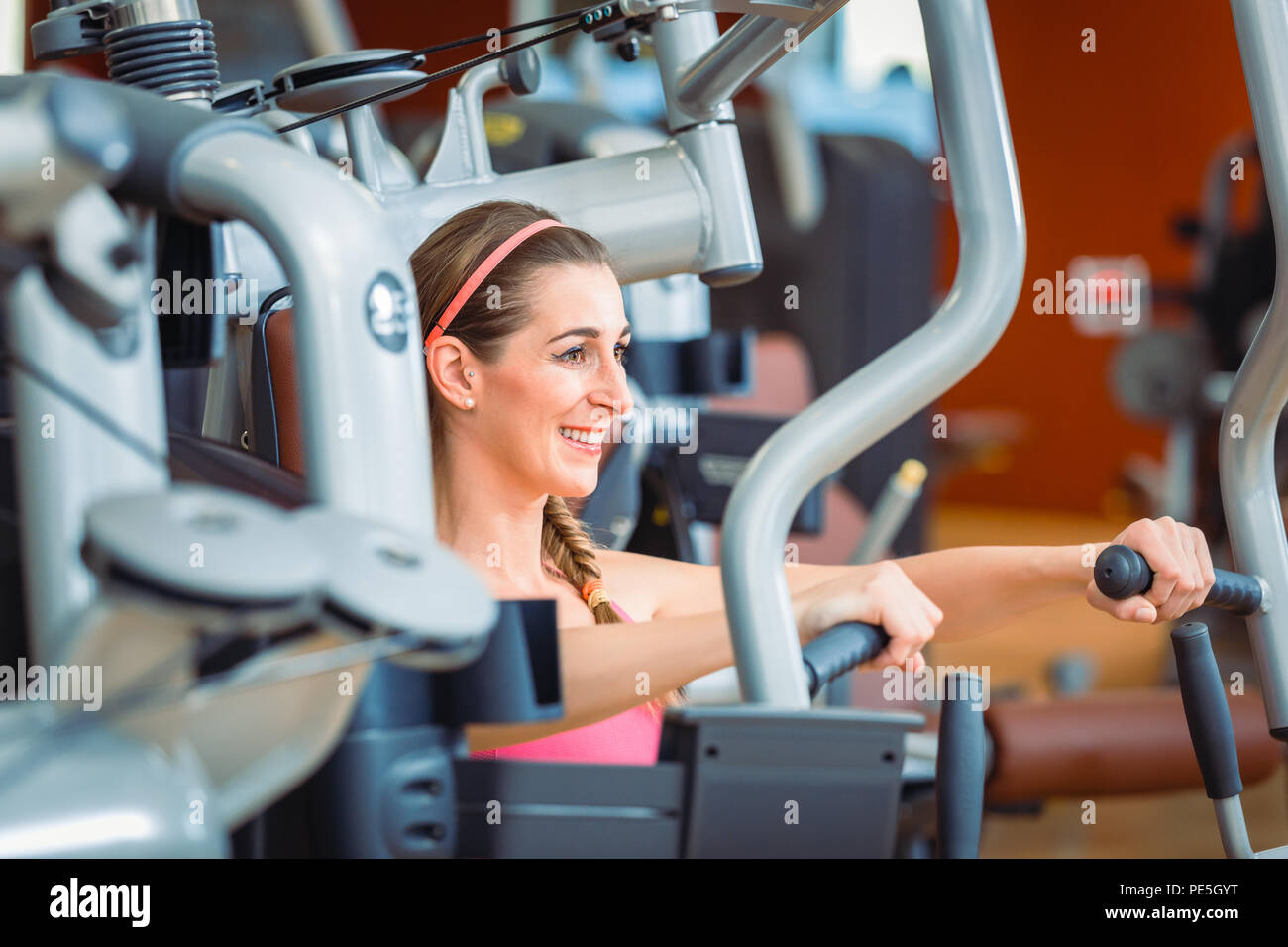 Side view of a cheerful woman exercising during upper-body workout Stock Photo