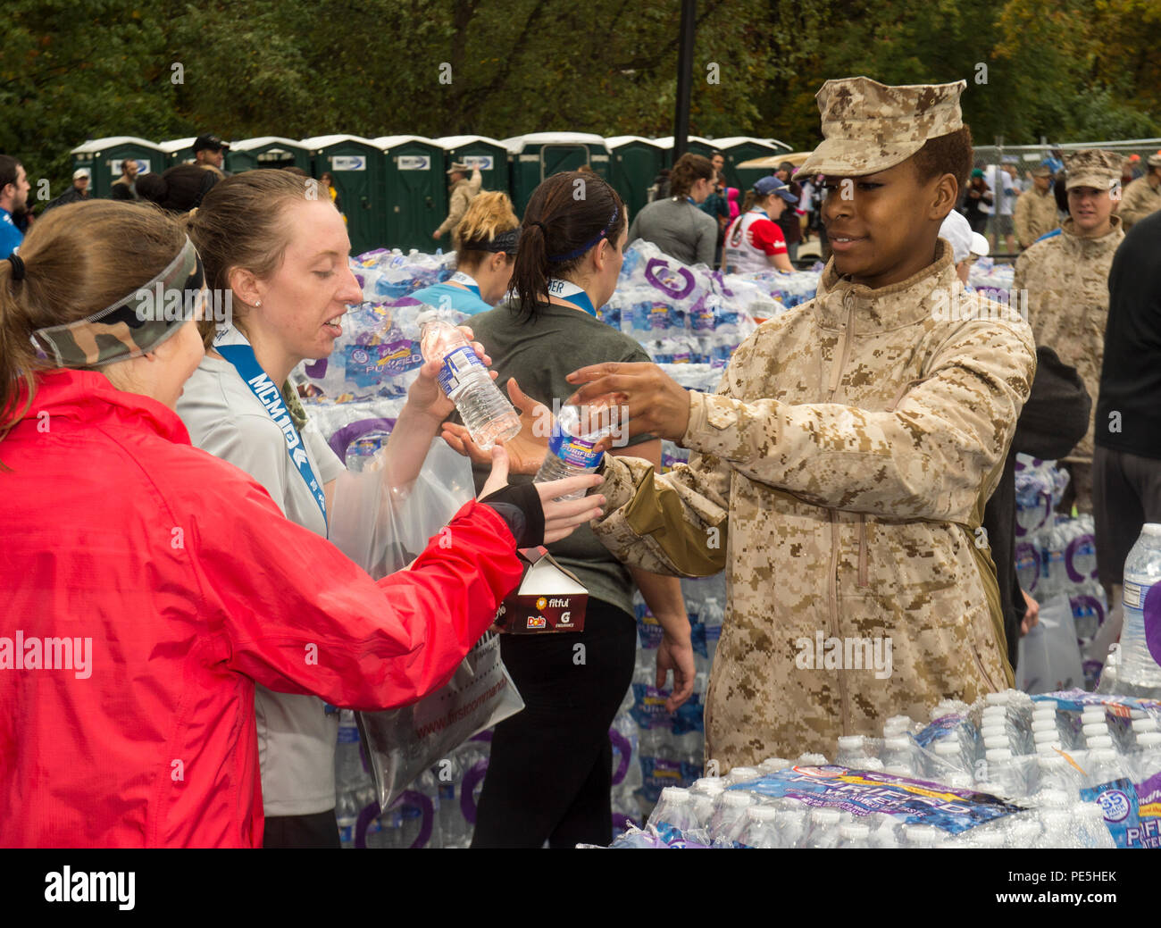U.S. Marine Corps Pfc. Shekinah L. Peake, student, Defense Information School, Fort George G. Meade, Md., gives water to the finishers of the 10K portion of the 40th Annual Marine Corps Marathon, Arlington, Va., Oct. 25, 2015. Known as 'The People's Marathon,' the 26.2 mile race, rated the third largest marathon in the United States, draws over 30,000 participants annually. (U.S. Marine Corps photo by Lance Cpl. Elisha N. Peake/Released) Stock Photo