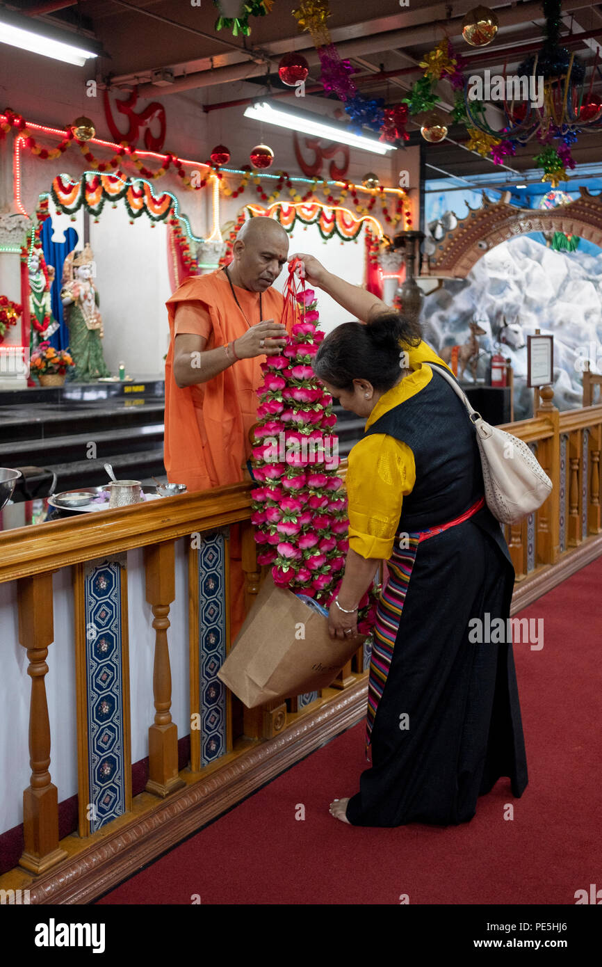 A worshipper from Tibet donating flowers to adorn the deities at a temple in Queens, New York. Stock Photo