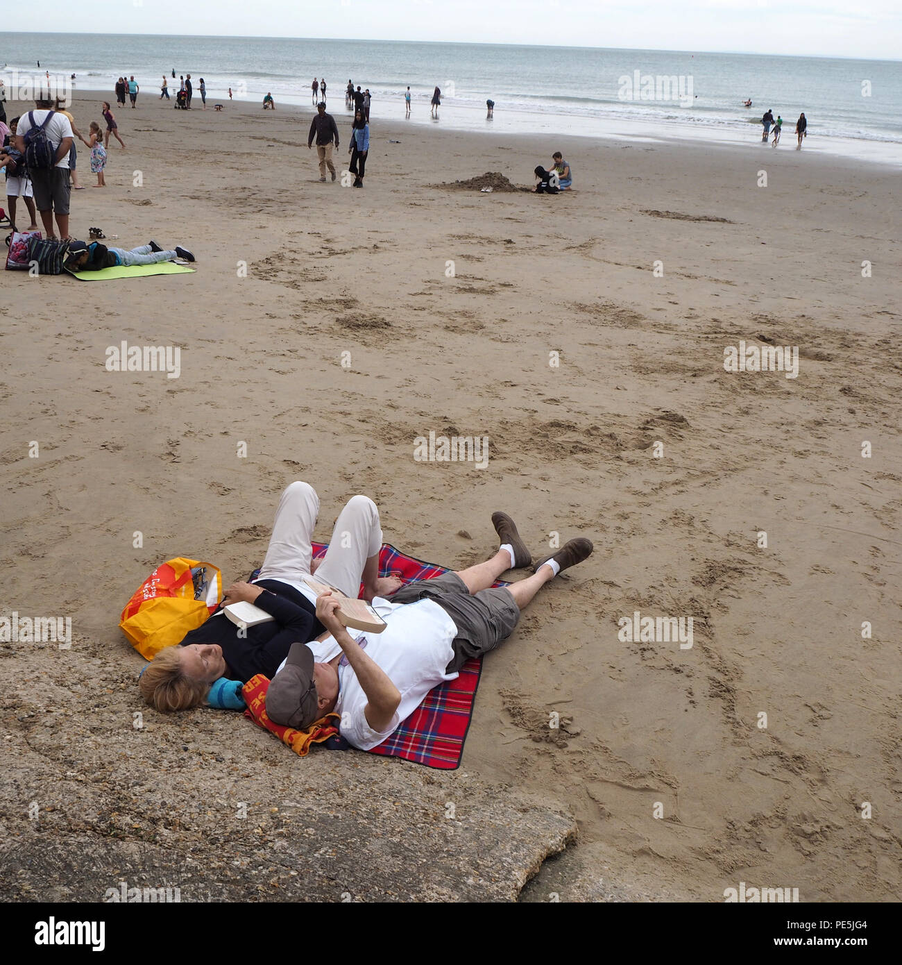 Couple relaxing on the beach reading books Stock Photo