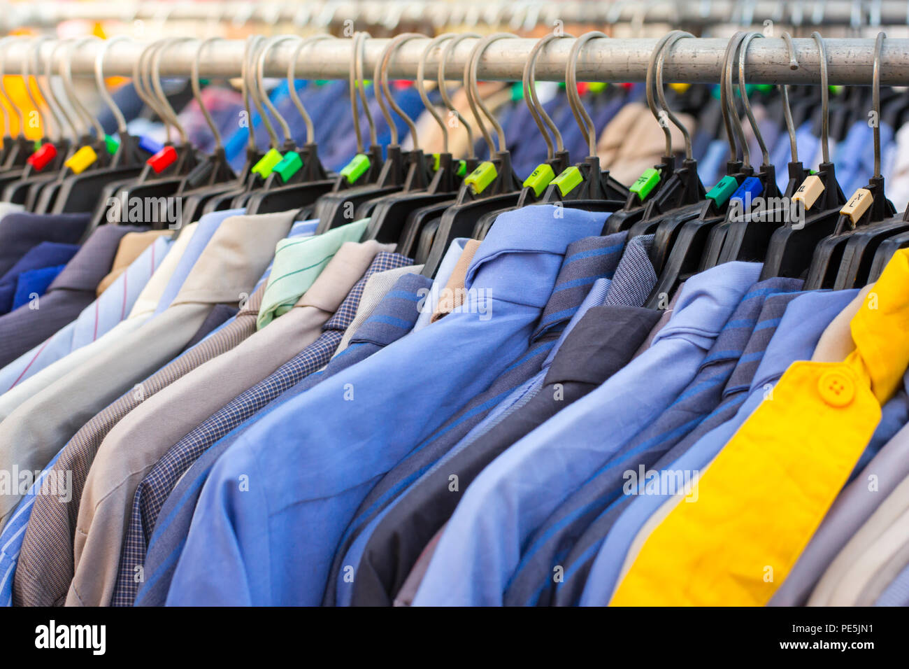Many shirts hanging on a rack in cloth shop Stock Photo - Alamy