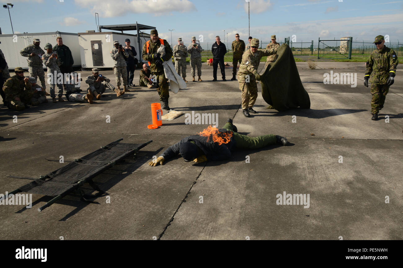 Instructor Tim Cranton, (with blanket), demonstrates how to put out a fire on a victim (Dr. Torsten Bengel) during the International Combat Lifesavers Course held Sept. 24, 2015, at the training area in Finthen, Germany. This is a multinational training with the U.S. Army Europe Medical Command.  (U.S. Army Photo by Visual Information Specialist Dee Crawford/Released) Stock Photo