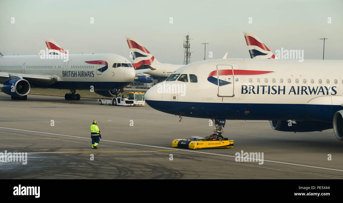 Airport worker operating a remote controlled tug at London Heathrow Airport to push back a departing British Airways Airbus A320 Stock Photo