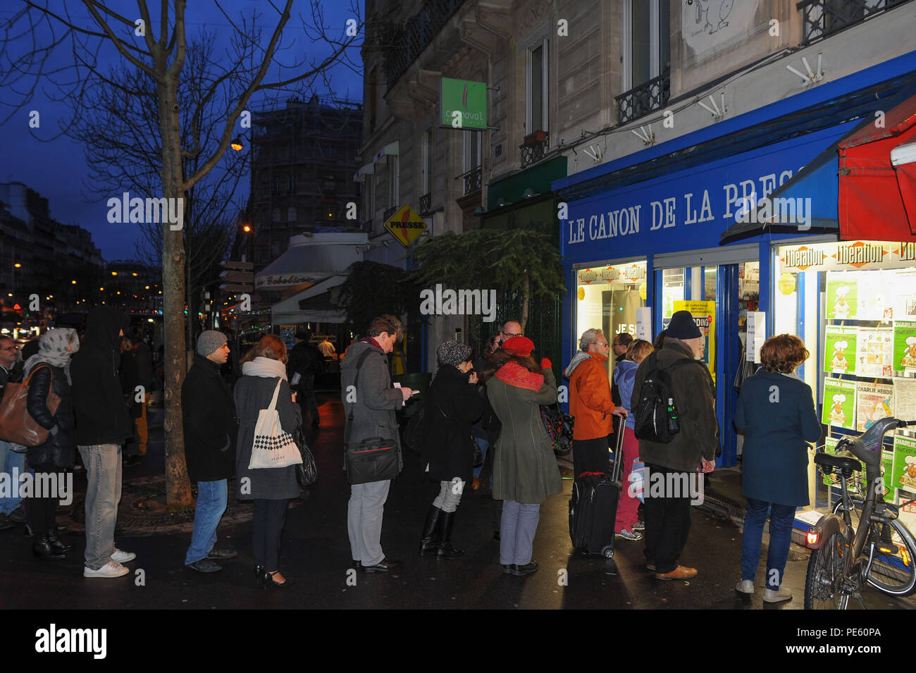 January 14, 2015 - Paris, France:  French people queue at a press kiosk as they wait to buy the latest issue of Charlie Hebdo magazine. Some 3 million copies of Charlie Hebdo - the survivors' issue, with a cartoon of prophet Muhammad on its cover - have been printed following a deadly shooting attack on its staff by Islamist gunmen. File d'attente devant un marchand de journaux pour la sortie du numero de survivants de Charlie Hebdo, une semaine apres l'attentat meurtrier contre sa redaction. La couverture est une caricature du prophete Mahomet avec une pancarte disant 'je suis Charlie'. *** F Stock Photo