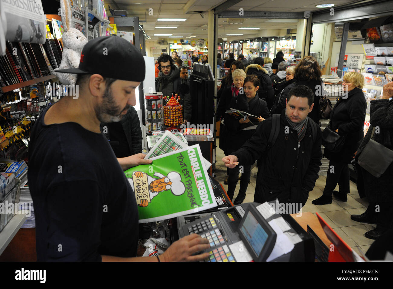 January 14, 2015 - Paris, France:  French people queue at a press kiosk as they wait to buy the latest issue of Charlie Hebdo magazine. Some 3 million copies of Charlie Hebdo - the survivors' issue, with a cartoon of prophet Muhammad on its cover - have been printed following a deadly shooting attack on its staff by Islamist gunmen. File d'attente devant un marchand de journaux pour la sortie du numero de survivants de Charlie Hebdo, une semaine apres l'attentat meurtrier contre sa redaction. La couverture est une caricature du prophete Mahomet avec une pancarte disant 'je suis Charlie'. *** F Stock Photo