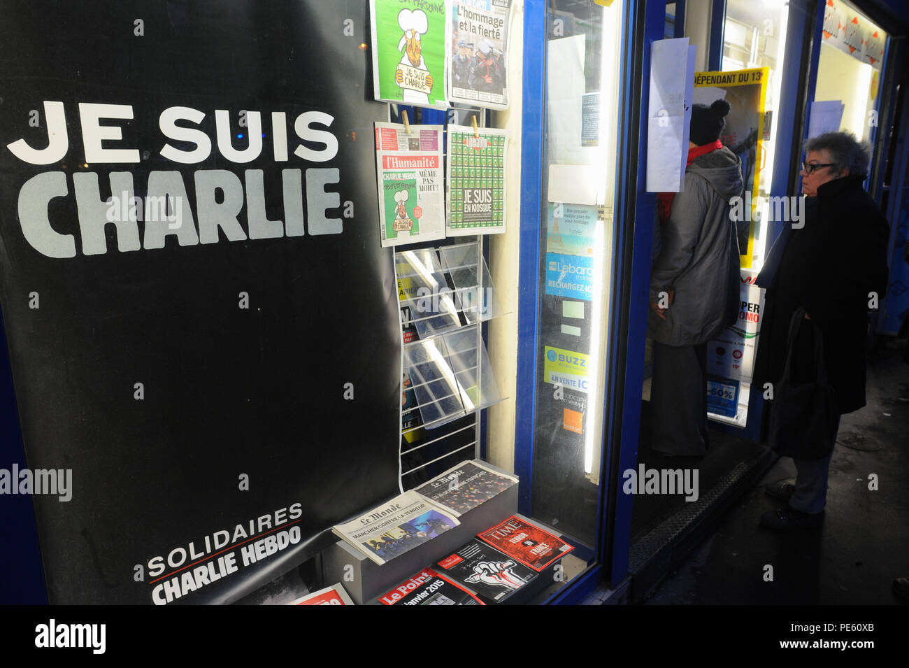 January 14, 2015 - Paris, France:  French people queue at a press kiosk as they wait to buy the latest issue of Charlie Hebdo magazine. Some 3 million copies of Charlie Hebdo - the survivors' issue, with a cartoon of prophet Muhammad on its cover - have been printed following a deadly shooting attack on its staff by Islamist gunmen. File d'attente devant un marchand de journaux pour la sortie du numero de survivants de Charlie Hebdo, une semaine apres l'attentat meurtrier contre sa redaction. La couverture est une caricature du prophete Mahomet avec une pancarte disant 'je suis Charlie'. *** F Stock Photo