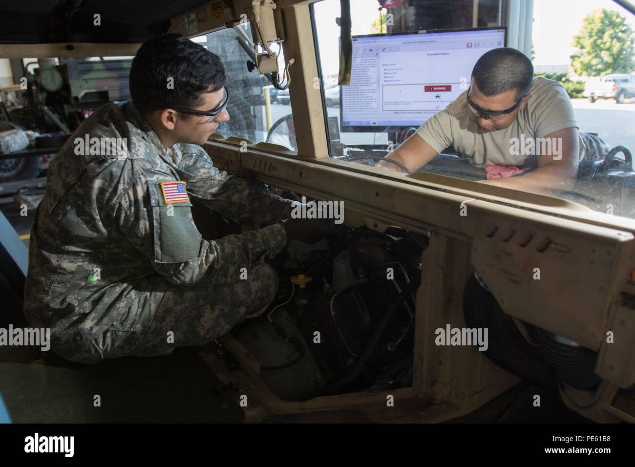 Arizona National Guard Pfc. Brandon A. Smith of Gilbert, Ariz., and Pfc. Fernando Mendoza of Chandler, Ariz., work on the fuel injector for an M1097 Humvee Sept. 18, 2015 at Camp Dodge Joint Maneuver Training Center in Johnston, Iowa. The two Soldiers are wheeled vehicle repairers in the 3666th Support Maintenance Company in Phoenix and at Camp Dodge with the 3666th SMC during its 15-day annual training. (U.S. Army National Guard photo by Staff Sgt. Brian A. Barbour) Stock Photo