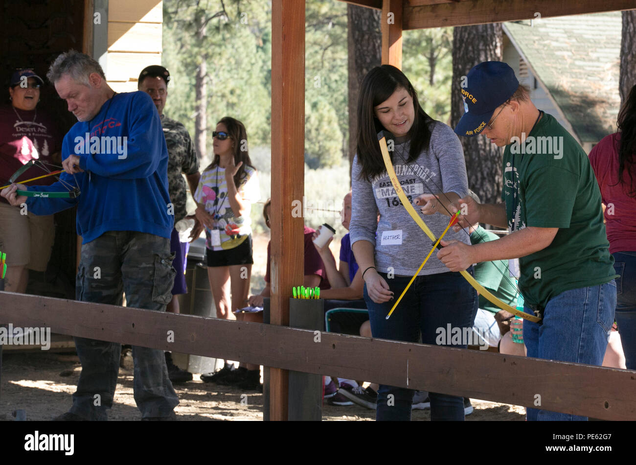 Heather Frausto, wife of Sgt. Nicholas Frausto, chaplain’s assistant, Protestant Chapel, helps a camper use a bow at the archery station of the Desert Arc Sports and Recreation Camp at Camp Ronald McDonald, Idyllwild, Calif., Oct. 3, 2015. (Official Marine Corps photo by Lance Cpl. Thomas Mudd/ Released) Stock Photo