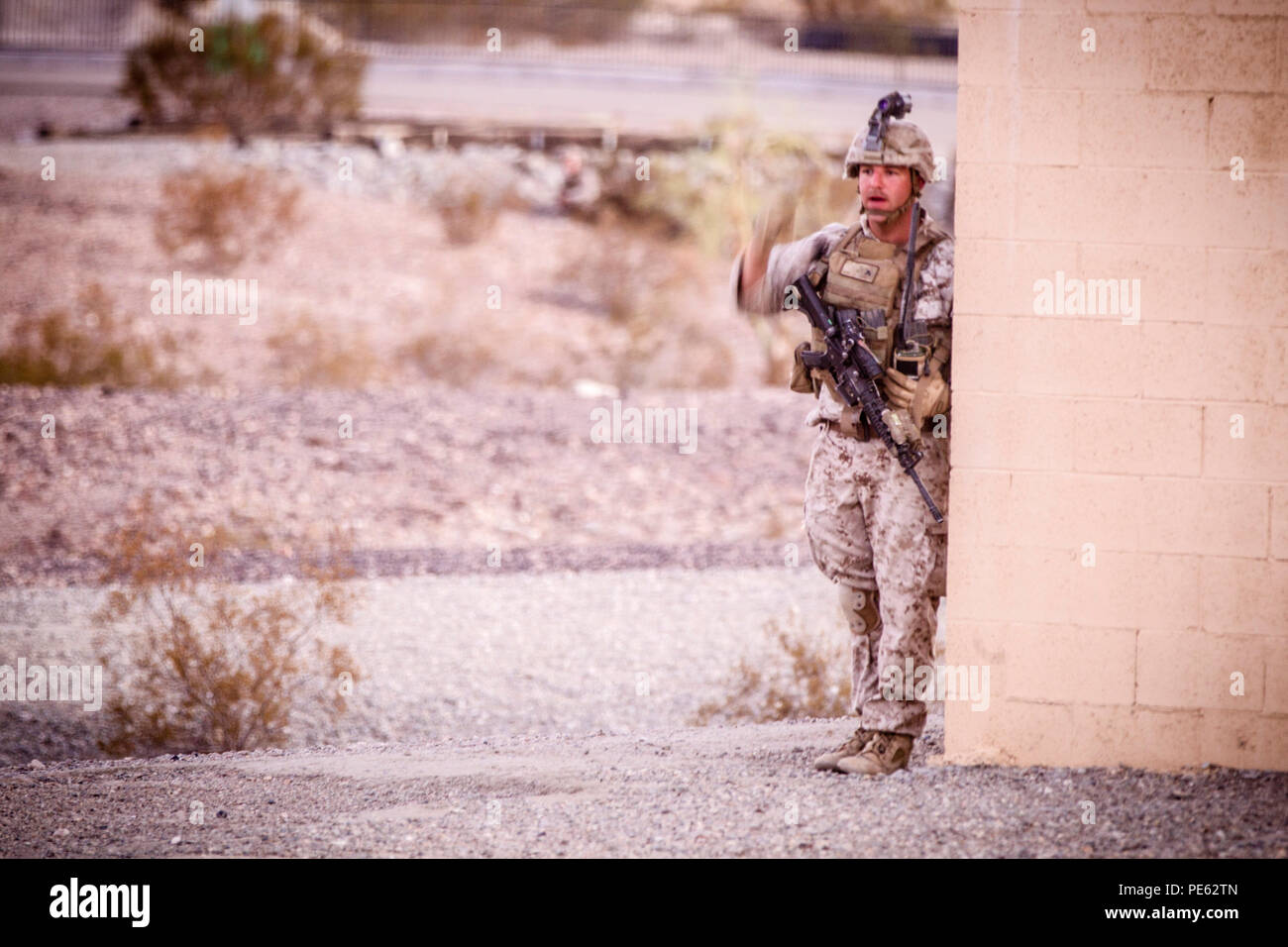 A U.S. Marine with 2nd Battalion, 7th Marine Regiment, 1st Marine Division signals to his team during a heavy Huey raid at K-9 Village, Yuma Proving Grounds, Ariz., Oct. 7, 2015. The exercise is part of Weapons and Tactics Instructor (WTI) 1-16, a seven-week training event hosted by Marine Aviation Weapons and Tactics Squadron One (MAWTS-1) cadre. MAWTS-1 provides standardized tactical training and certification of unit instructor qualifications to support Marine Aviation Training and Readiness and assists in developing and employing aviation weapons and tactics. (U.S. Marine Corps photograph  Stock Photo