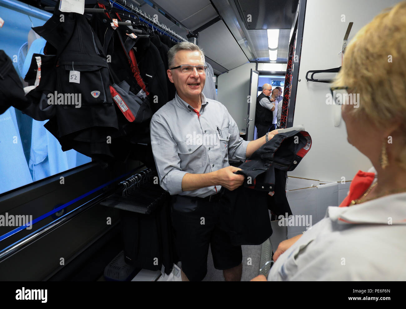 Hamburg, Germany. 13th Aug, 2018. Bus driver Andreas Hinze gets a pair of shorts for fitting from Christine Augustin, Service Hochbahn Clothing (SHK), in the clothes bus of the Hochbahn. The summer heat has an impact on the dress code for Hamburg's bus and train drivers, who are currently wearing around 1000 short black trousers. Credit: Christian Charisius/dpa/Alamy Live News Stock Photo