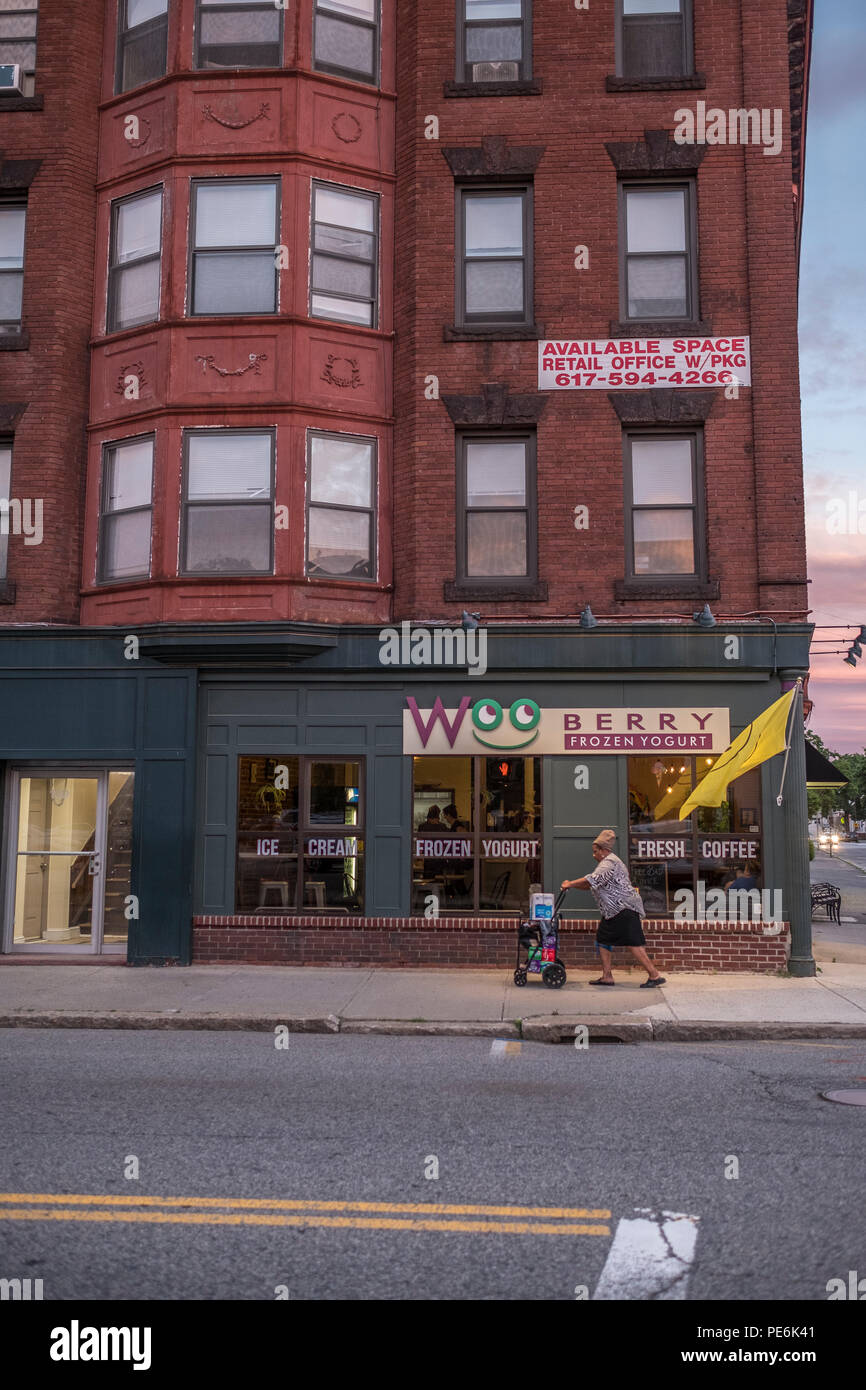 A woman pushes a baby carriage by Woo Berry on Highland Street in Worcester, MA is a favorite place to get great frozen yogurt Stock Photo