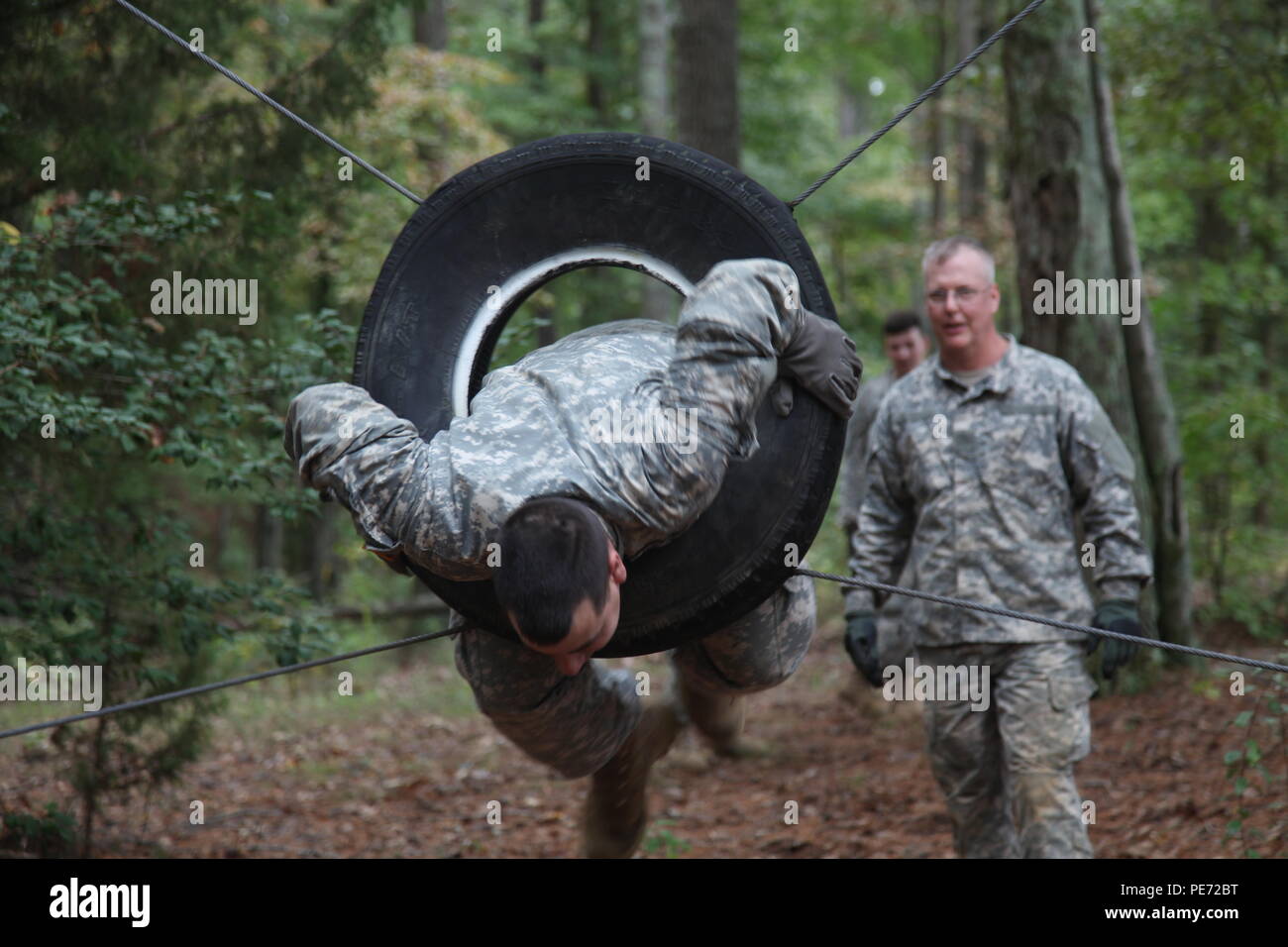 U.S. Army Sgt. Robert Sheets, assigned to 55th Signal Company (Combat Camera), jumps through a tire during a wire obstacle course as part of a Field Training Exercise (FTX) at Fort AP Hill, Va., Sept. 28, 2015. The 55th Signal Company conducts a FTX twice a year in order to maintain tactical proficiency, as well as to develop and prepare Soldiers for the rigor of combat. (U.S. Army photo by Pfc. Elliott Page/Released). Stock Photo