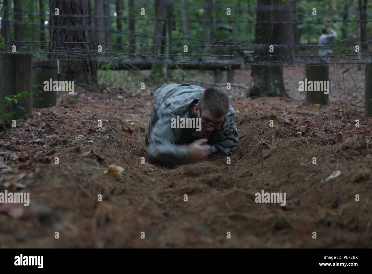 U.S. Army Pfc. Ian Ryan, assigned to 55th Signal Company (Combat Camera), high crawls under barbed wire while going through an obstacle course during a Field Training Exercise (FTX) at Fort AP Hill, Va., Sept. 28, 2015. The 55th Signal Company conducts a FTX twice a year in order to maintain tactical proficiency, as well as to develop and prepare Soldiers for the rigor of combat. (U.S. Army photo by Pfc. Elliott Page/Released). Stock Photo