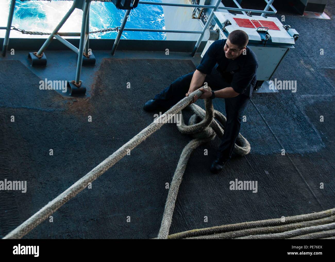 A Boatswain's Mate fakes down a mooring line on the fantail of USS John ...