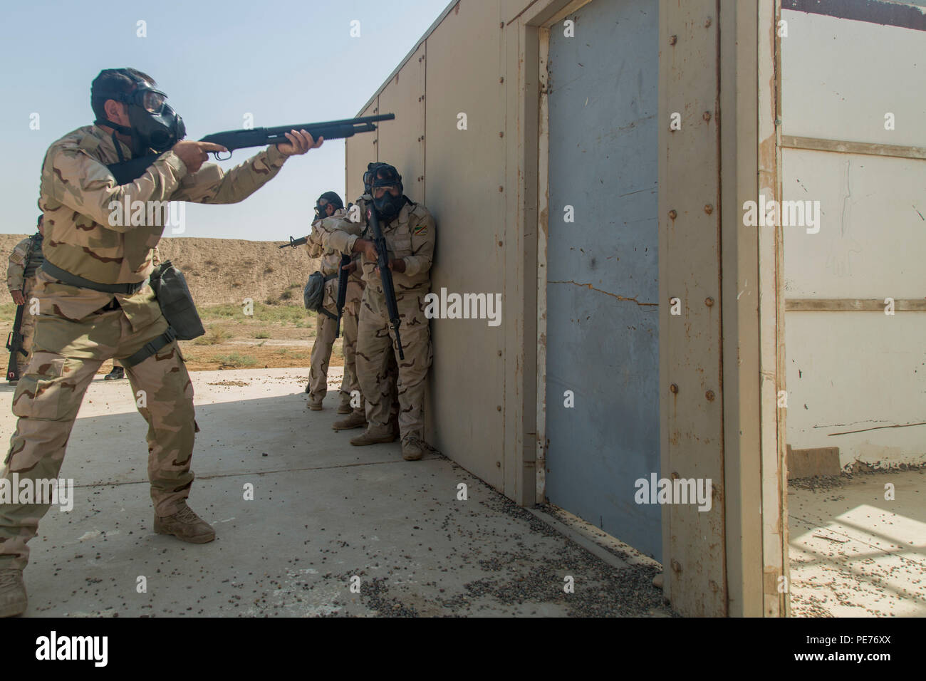 Iraqi soldiers assigned to the 71st Iraqi Army Brigade prepare to breach a door during protective mask training at Camp Taji, Iraq, Oct. 15, 2015. Iraqi soldiers were performing basic drills while wearing a protective mask in order to simulate the vigorous environment created by a biochemical attack. Participating in this type of training at the Camp Taji building partner capacity site will prepare the soldiers for potential biochemical attacks when fighting against the Islamic State of Iraq and the Levant. (U.S. Army photo by Spc. William Marlow/Released) Stock Photo