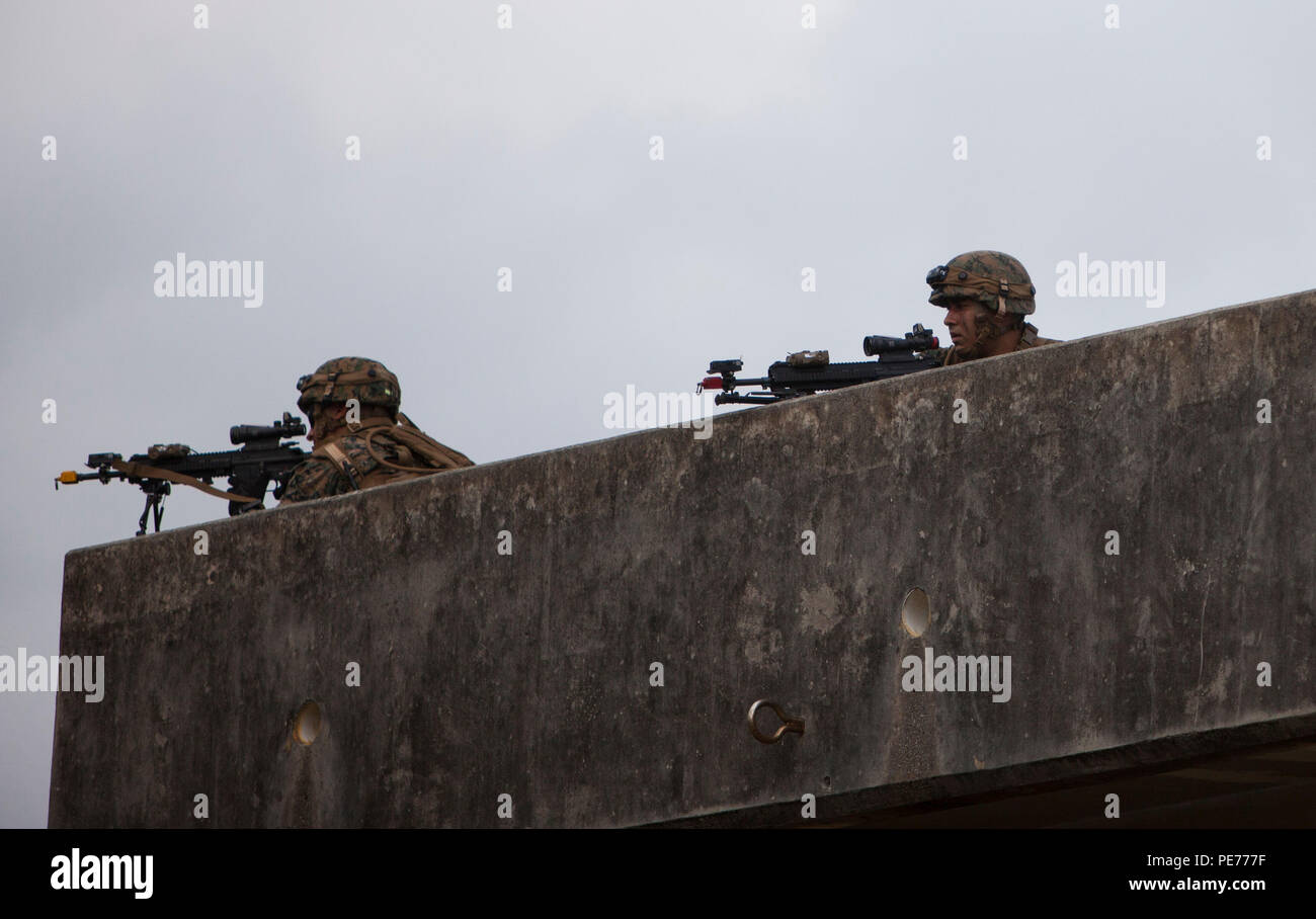 Marines provide over watch security during a raid on Combat Town, at the Central Training Area, Okinawa, Japan, Oct. 26, 2015. The raid was part of Blue Chromite 2016, a large-scale amphibious exercise that achieves high-level training at a low cost, while keeping naval forces in a forward-deployed posture. During Blue Chromite, participating units take advantage of on-island training resources, saving in transportation and logistics cost. The Marines are with Alpha Company, 1st Battalion, 2nd Marine Regiment, currently assigned to 4th Marine Regiment, 3rd Marine Division, III Marine Expeditio Stock Photo