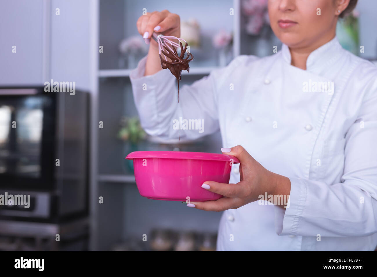 Beautiful baker holding pink bowl with chocolate mousse Stock Photo