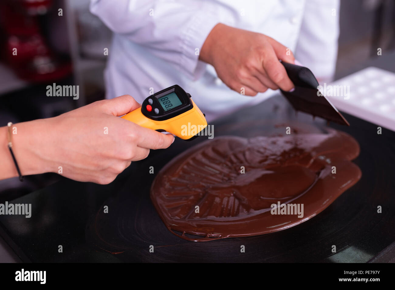 Pastry chef measuring the temperature of the chocolate with an infrared  thermometer, working on the tempering of the chocolate Stock Photo - Alamy