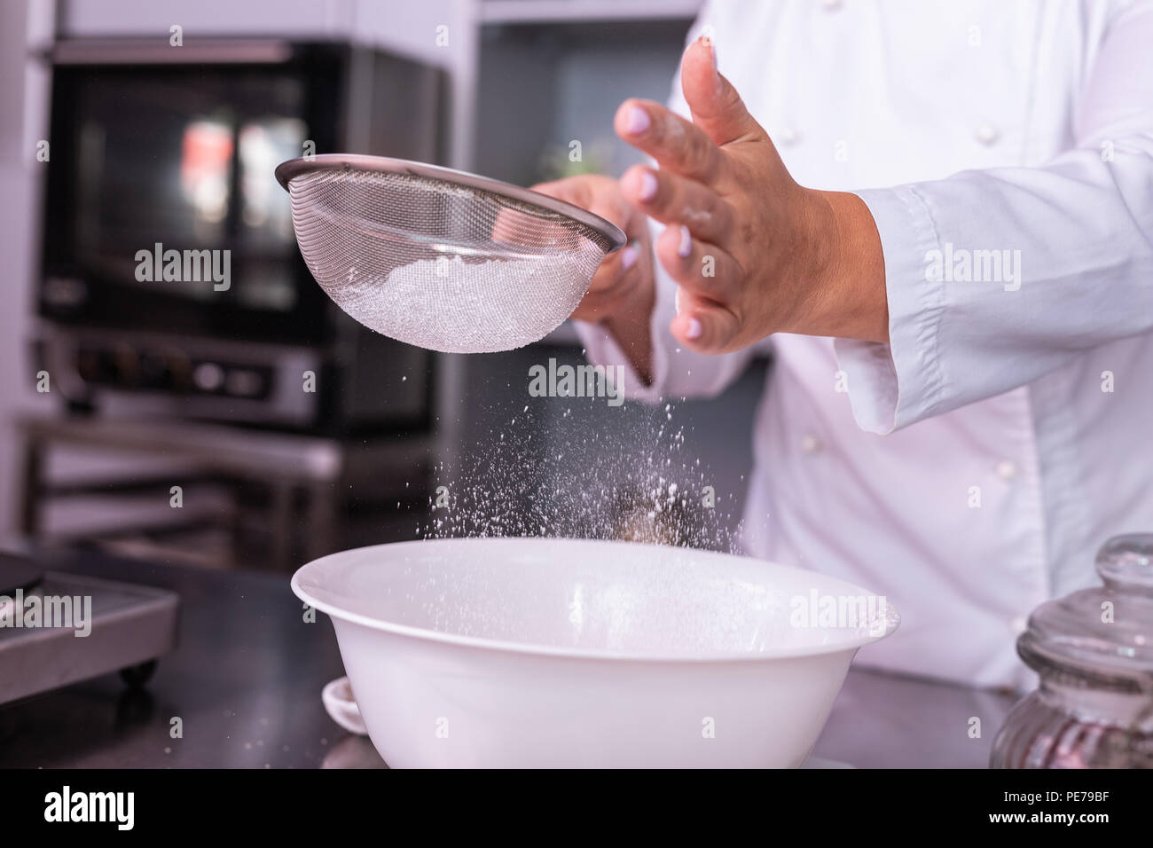 Master of confectionery sieving the flour preparing ingredients for pie