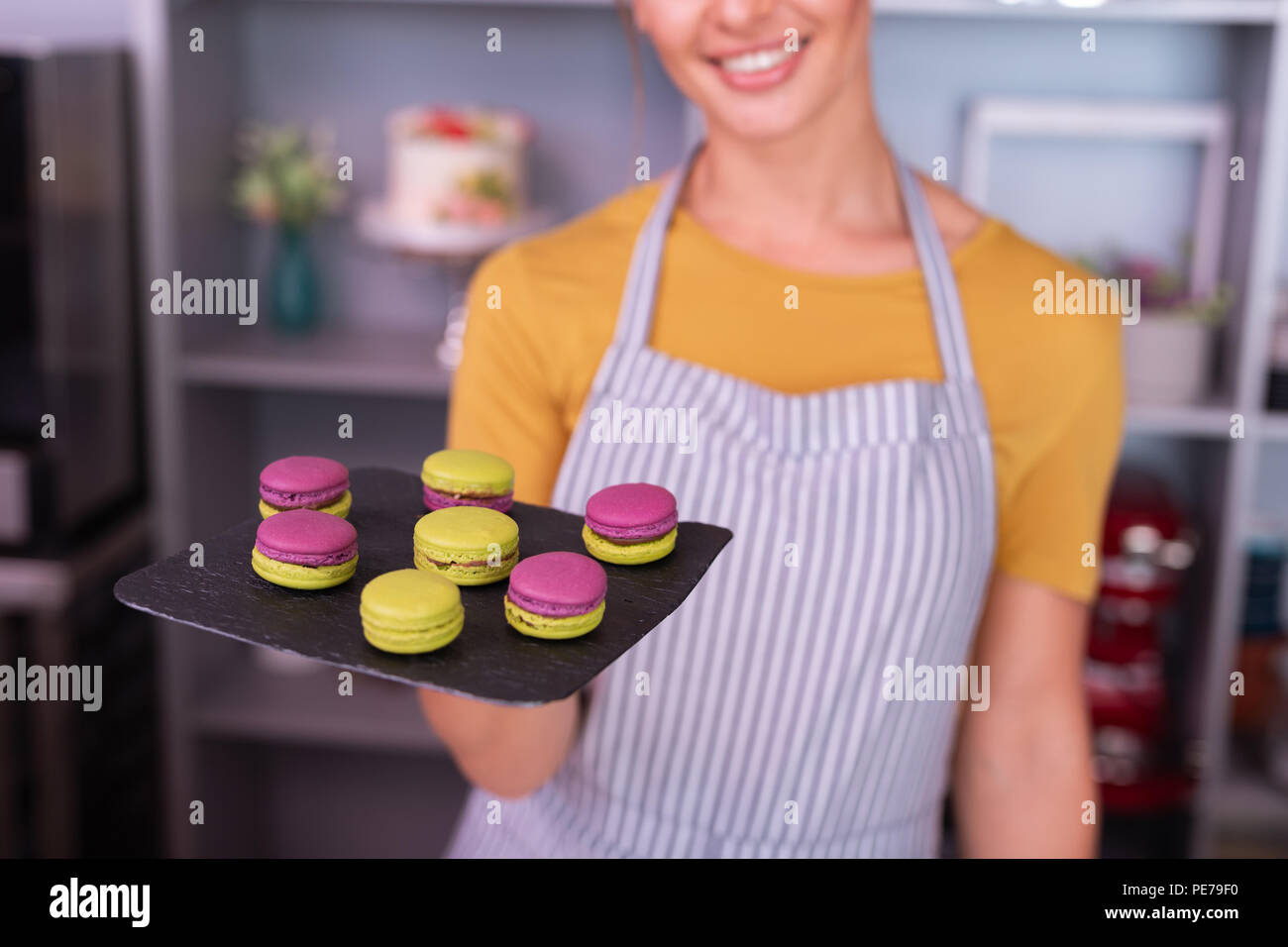 Young baker smiling broadly after cooking bright macaroons Stock Photo