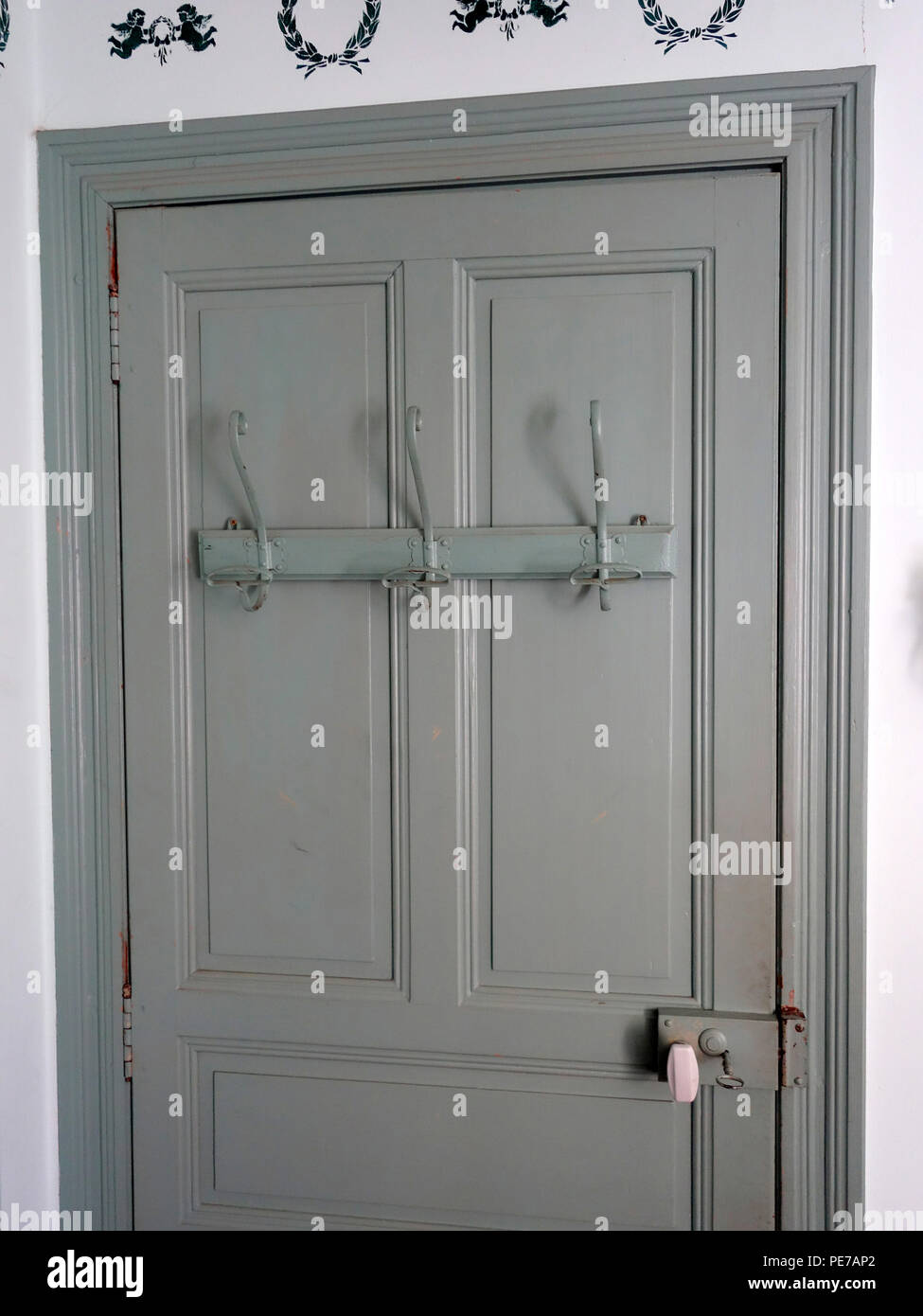 French Antique 3 metal coat hooks mounted on a metal bar on a french village house interior door Stock Photo Alamy