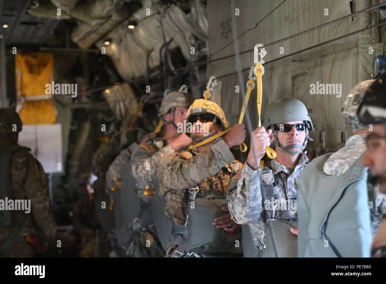 U.S. Army paratroopers assigned to Tarantula Team, Operations Group hook up static  lines inside a C-130 aircraft, before conducting airborne operations at the  National Training Center, Fort Irwin, Calif., Oct. 27 2015.