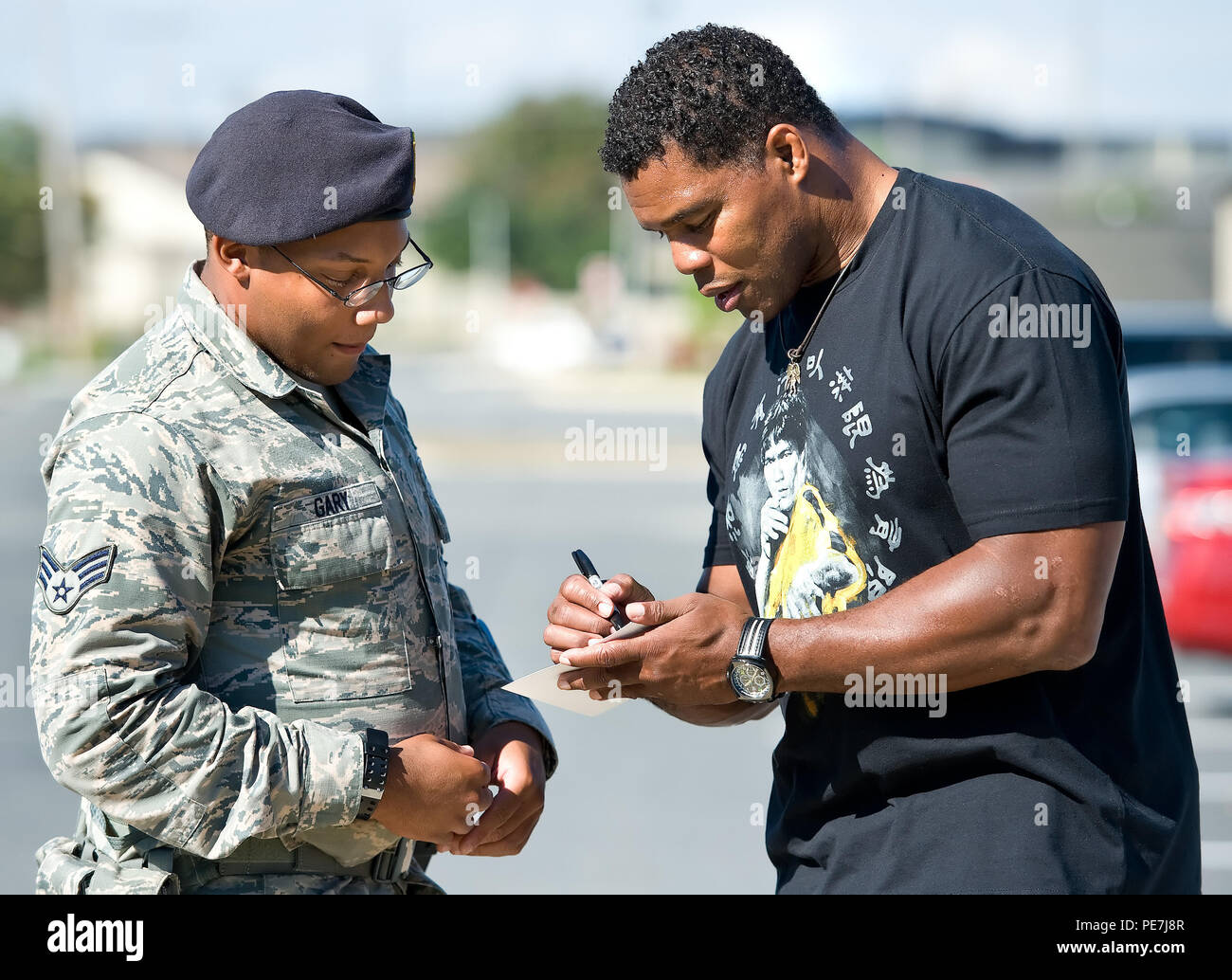 Former NFL running back and 1982 Heisman Trophy winner Herschel Walker, right, autographs a photo for Senior Airman Vernon Gary, 512th Security Forces Squadron response force leader, left, Oct. 13, 2015, on Dover Air Force Base, Del. At each stop on his base tour, Walker autographed photos and answered personal and sports-related questions from Team Dover members. (U.S. Air Force photo/Roland Balik) Stock Photo