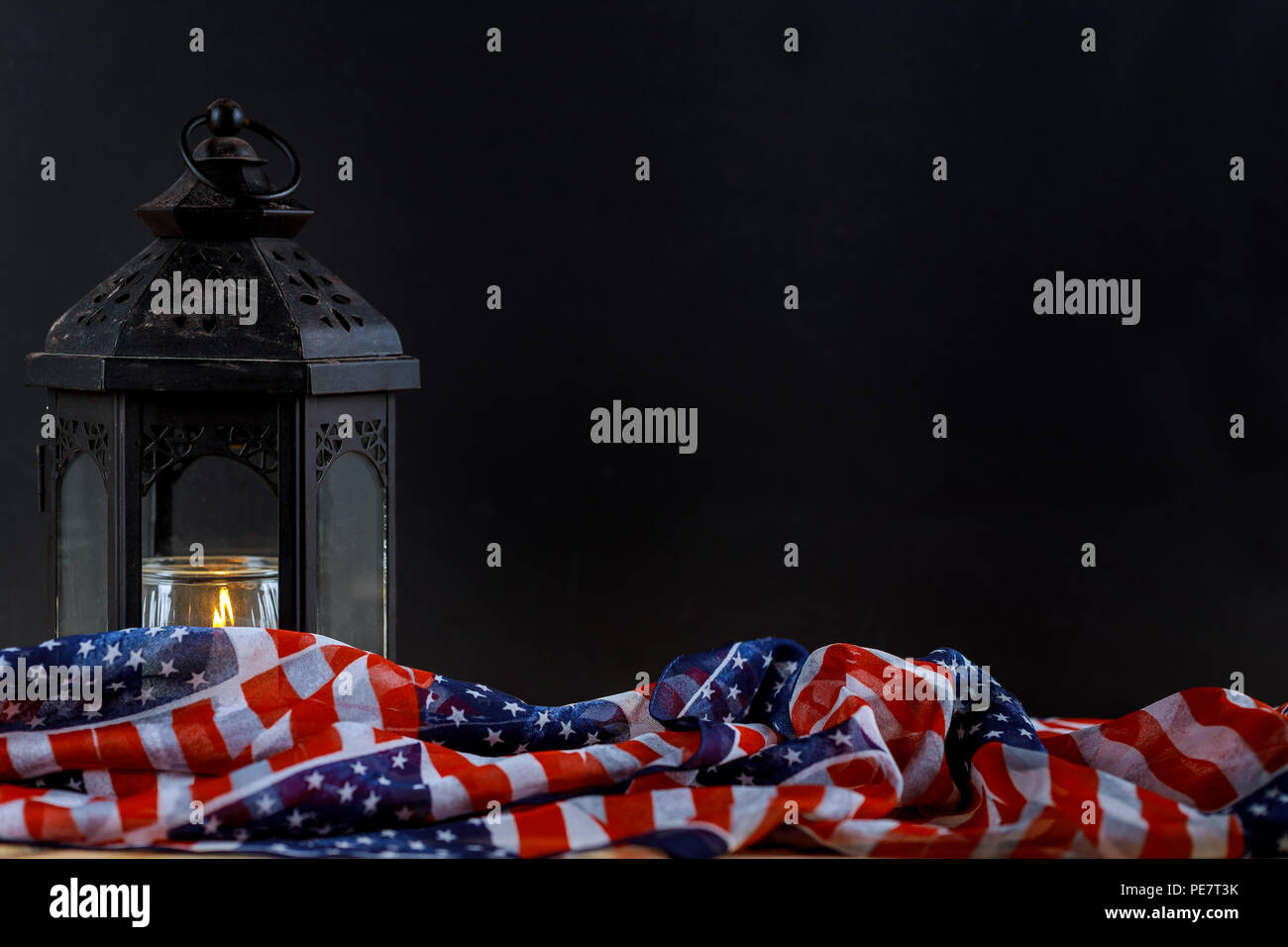 The flag of the United States and lighted candles, black background