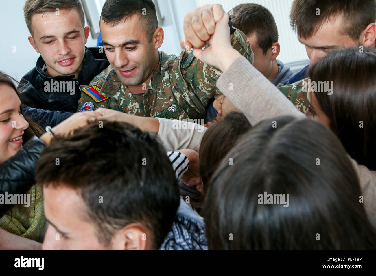 An Armenian Soldier serving in Kosovo with Multinational Battle Group-East leads a group of students attending a Violence Free Future tolerance event through a game called The Human Knot, Oct. 17, 2015, in Kacanik, Kosovo. During the game, the students used teamwork and communication skills to untangle themselves without letting go of each other’s hands. Several members of MNBG-E volunteered their time to lead this and other games used to simulate real-life situations and start conversations about stereotypes, respect and overcoming differences. (U.S. Army photo by Staff Sgt. Mary Junell, Mult Stock Photo