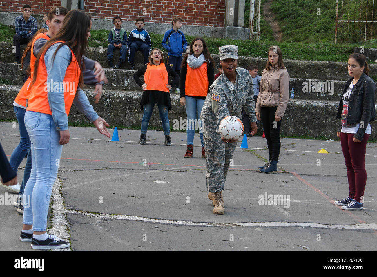 Sgt. Travanda Burton, a U.S. Army Reserve Soldier deployed to Kosovo with the 345th Combat Support Hospital, throws a soccer ball for a group of students attending a Violence Free Future youth tolerance event Oct. 17, 2015, in Kacanik, Kosovo, as part of a game used to mimic real-life situations involving stereotypes. Burton and several other Multinational Battle Group-East members volunteered their free time to lead the games, which aim to promote pro-social behavior among Kosovo’s youth. (U.S. Army photo by Staff Sgt. Mary Junell, Multinational Battle Group-East) Stock Photo