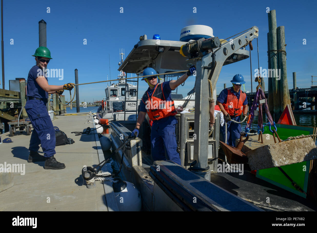 Left to right - Fireman Brittany Barba, Petty Officer 2nd Class Justin Thornton, and Petty Officer 3rd Class Collin Blugis conduct a dynamic load test on the crane onboard the 26-Foot Trailerable Aids to Navigation Boat from Coast Guard Aids to Navigation Team Crisfield, Md., Wednesday, Oct. 21, 2015. Crew members from ANT Crisfield were performing davit inspections, as well as static and dynamic load tests for the crane aboard the TANB.  (U.S. Coast Guard photo by Petty Officer 2nd Class David Marin) Stock Photo