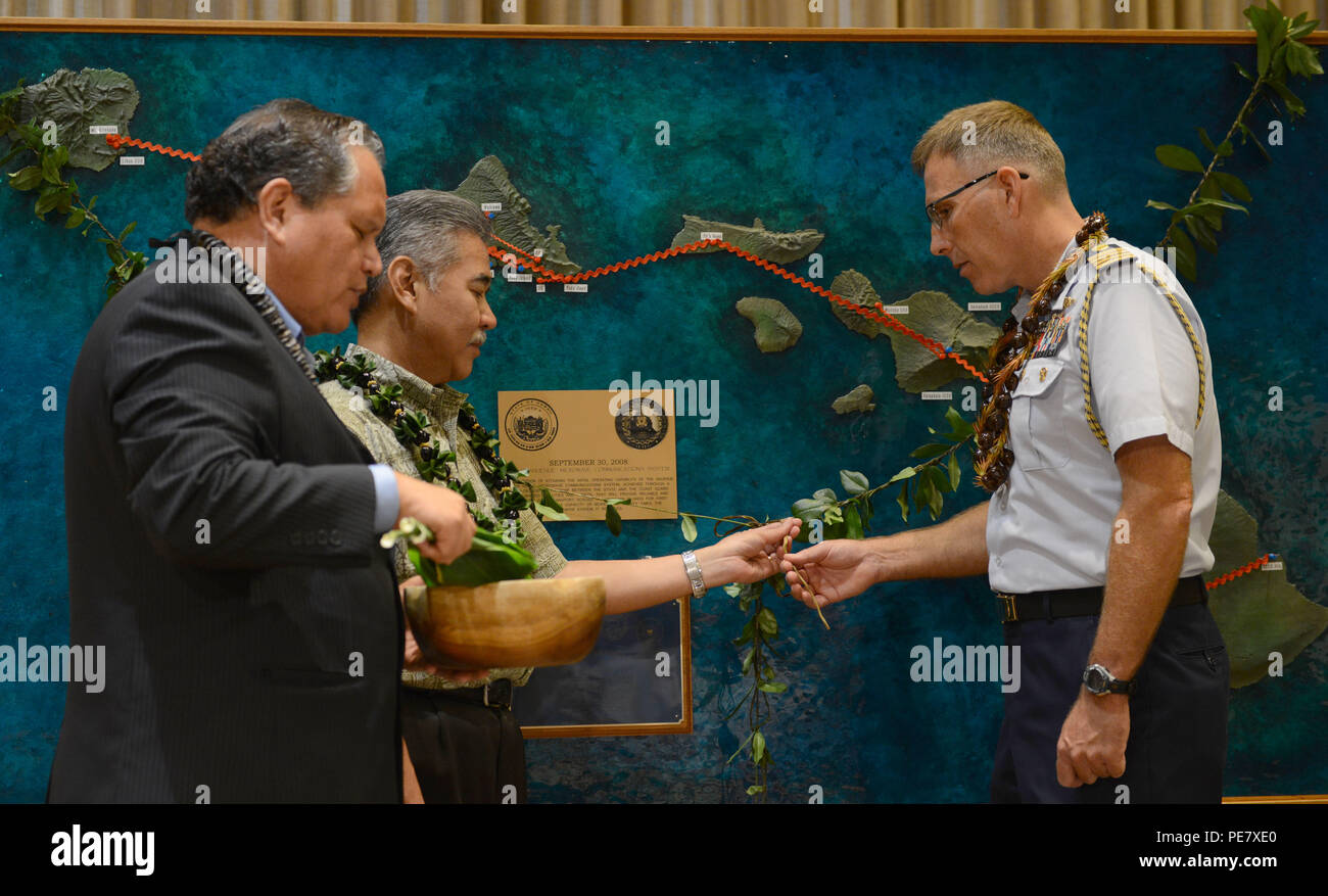 Kahu Kelekona Bishaw leads David Ige, Hawaii state governor, and Capt. James Jenkins, Coast Guard 14th District chief of staff, through a ceremonial blessing to acknowledge the spirit of laulima represented by a partnership between the state of Hawaii and the Coast Guard after announcing the completion of the Anuenue Interisland Digital Microwave Network, at the Hawaii State Capitol in Honolulu, Oct. 22, 2015. The Anuenue IDMN consists of high-capacity microwave links, radio towers, and facility buildings that interconnect and support the systems and networks relied upon by first responders, s Stock Photo