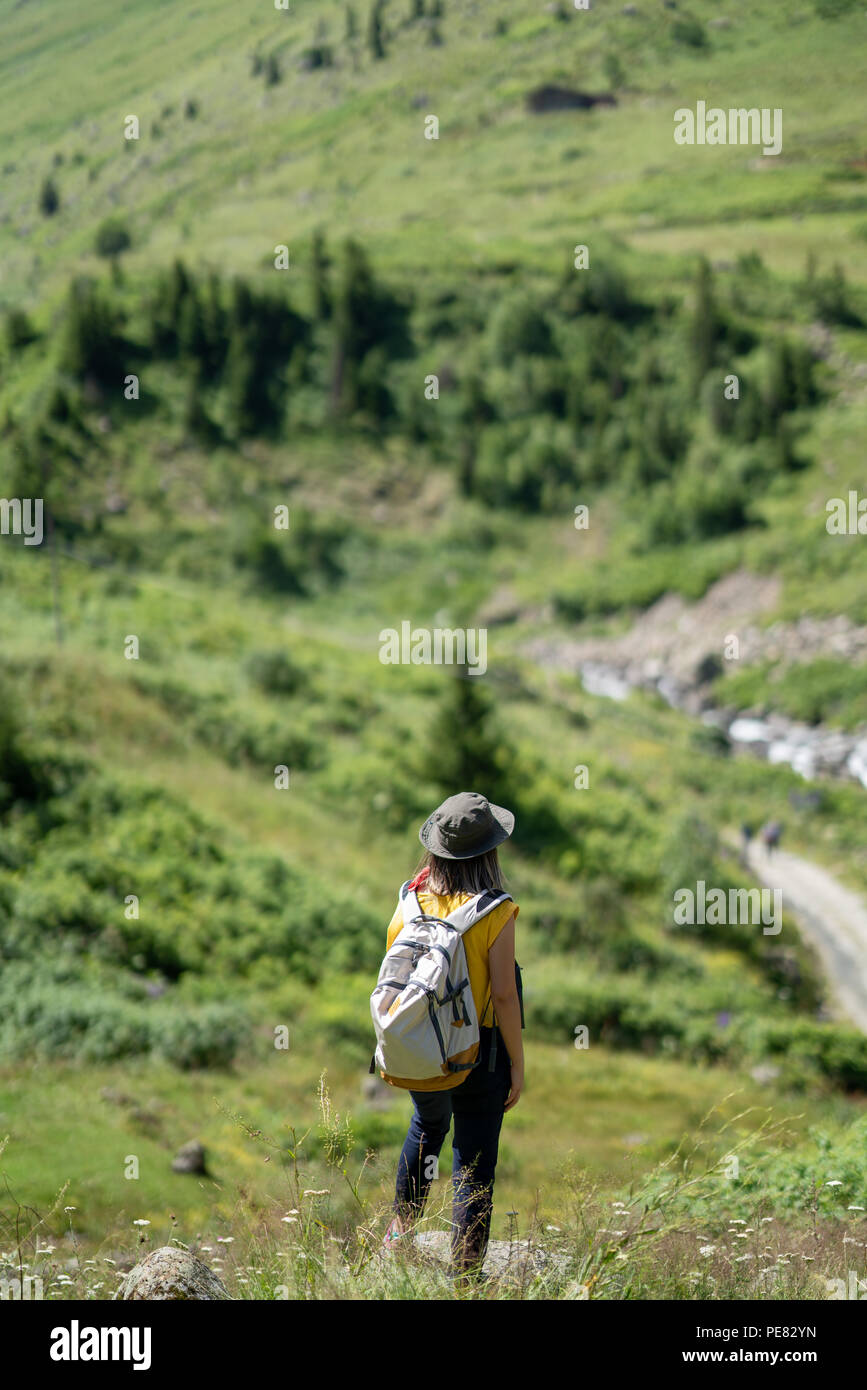Woman with backpack standing on the rock and looking at view Stock Photo