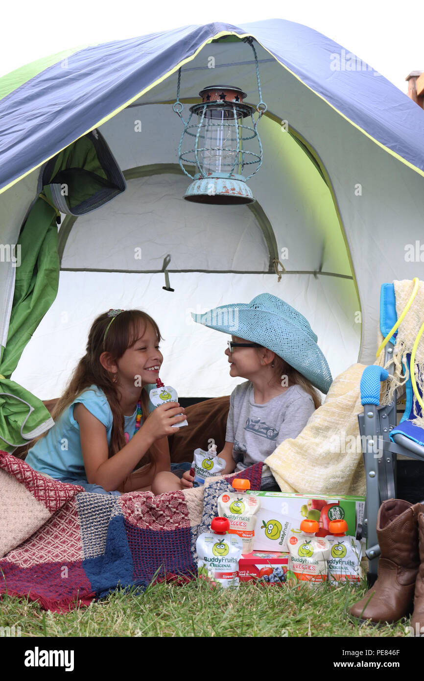 Two girls having fun camping with their Buddy Fruits Stock Photo