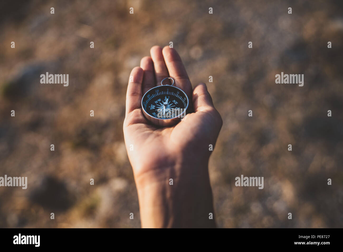 Hand holding compass looking for direction. Navigation, searching, exploring concept Stock Photo